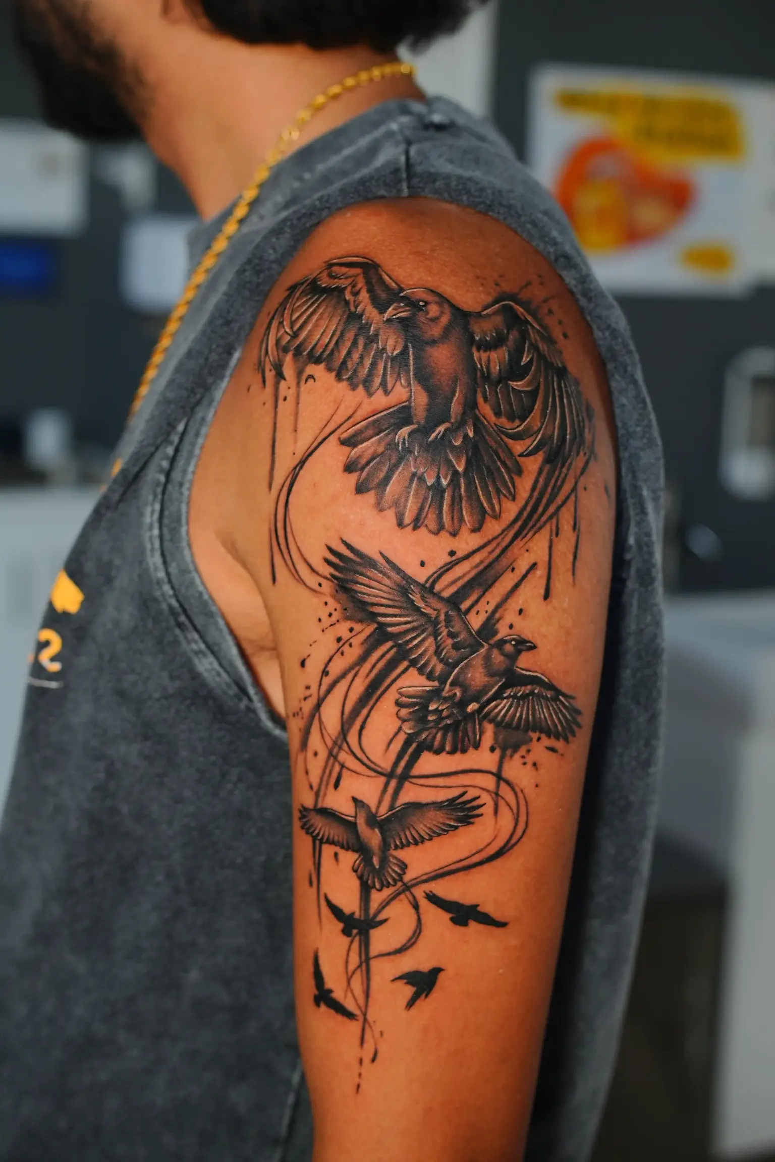 Black and grey tattoo of three birds in flight with sweeping linework on the upper arm