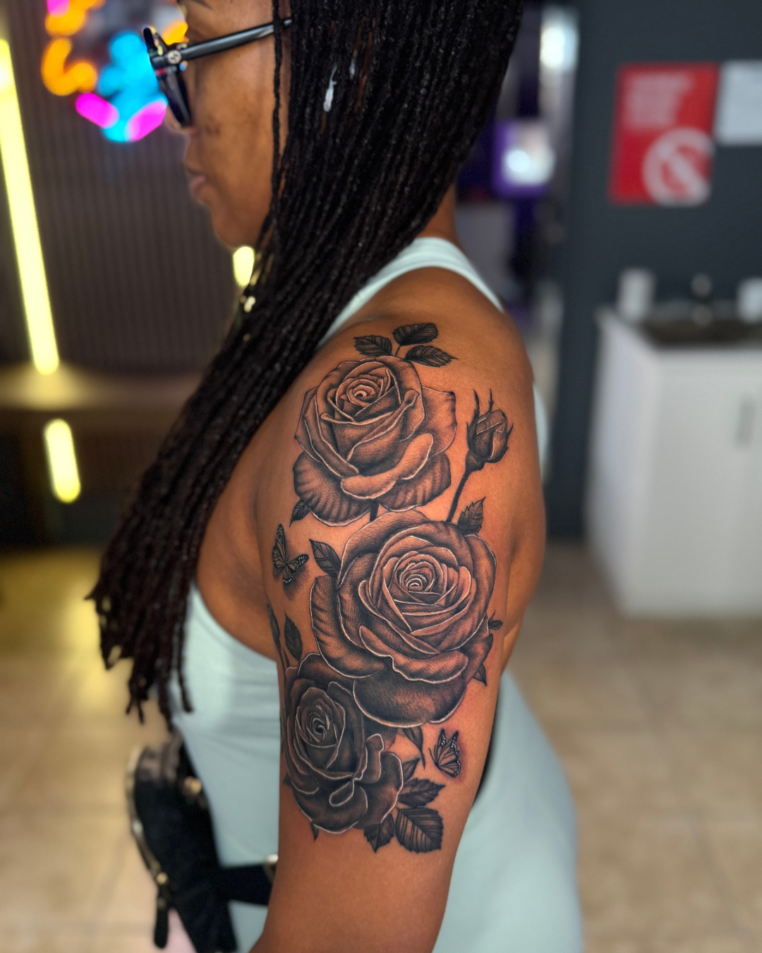 Black and grey large rose floral tattoo on the upper arm and shoulder