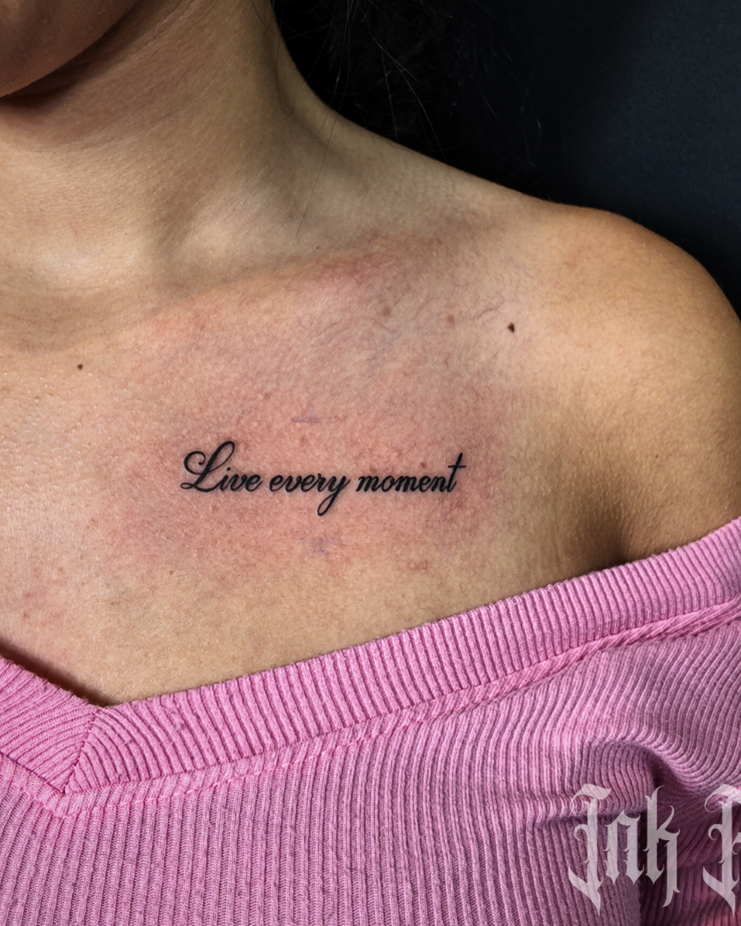 Fine line cursive script tattoo reading Live every moment on the collarbone area